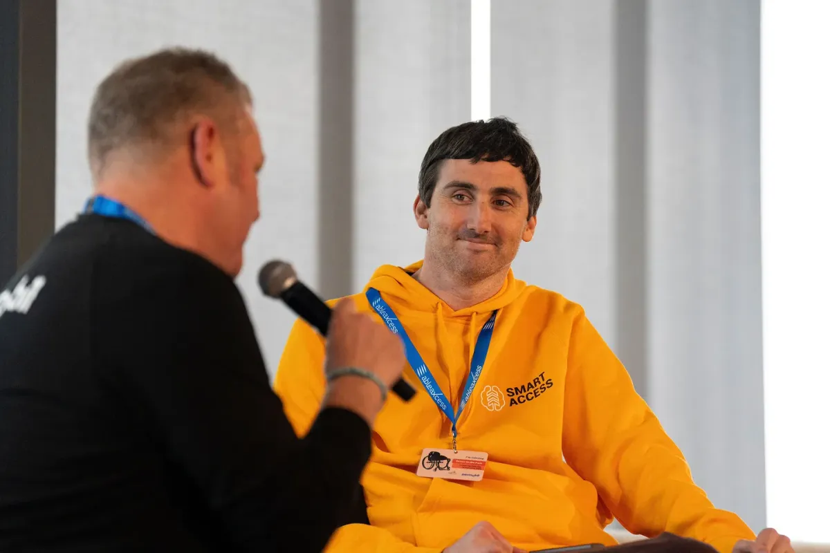 Tim Young in a yellow Smart Access hoodie, speaking with an interviewer